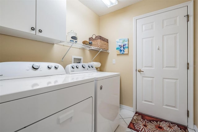 laundry area featuring light tile patterned floors, washer and clothes dryer, and cabinets