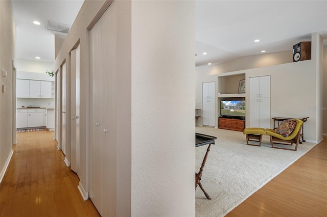 corridor featuring recessed lighting, visible vents, lofted ceiling, and light wood finished floors