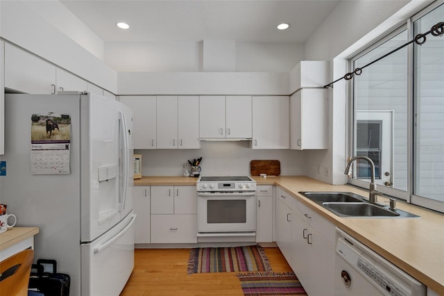 kitchen with white appliances, light wood-style flooring, light countertops, white cabinetry, and a sink