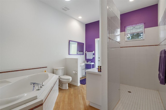 bathroom featuring a garden tub, toilet, vanity, wood finished floors, and walk in shower