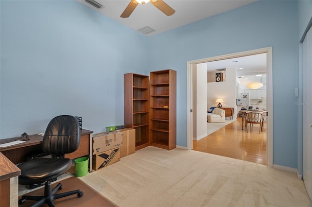 office space with light colored carpet, visible vents, ceiling fan, and baseboards