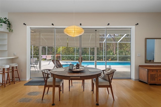 dining space featuring a sunroom, baseboards, and wood finished floors