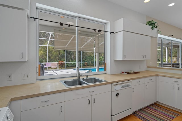 kitchen featuring light countertops, white dishwasher, a sink, and white cabinetry