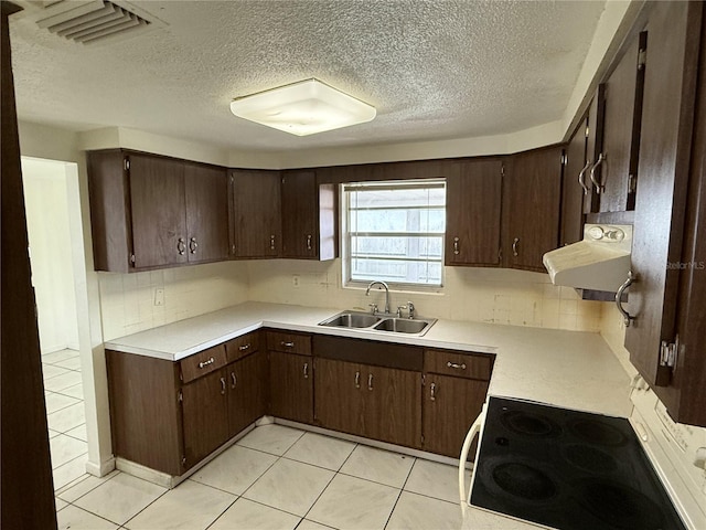 kitchen with sink, light tile patterned floors, dark brown cabinets, tasteful backsplash, and a textured ceiling