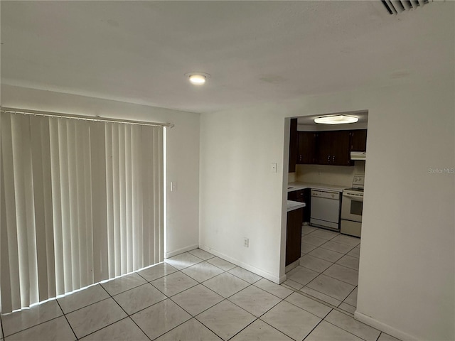 kitchen featuring dark brown cabinetry, light tile patterned flooring, and white appliances