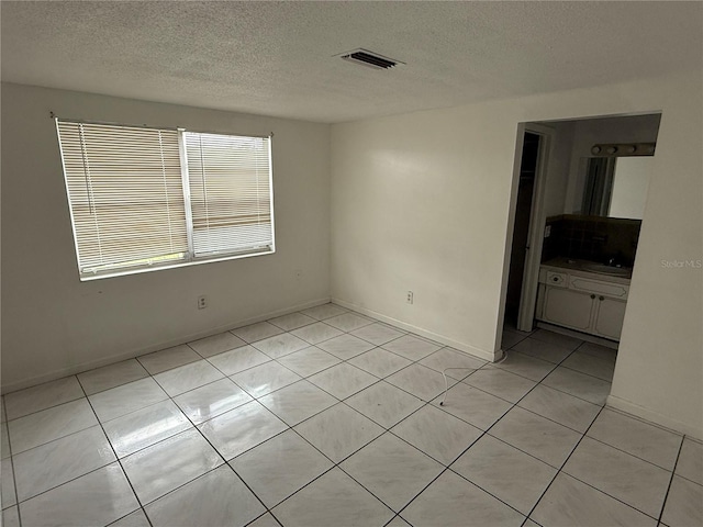 empty room featuring light tile patterned floors and a textured ceiling