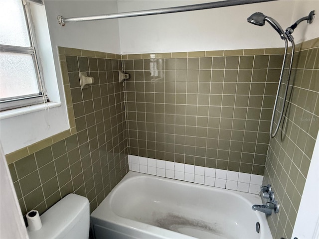 bathroom with tiled shower / bath, tile walls, and toilet