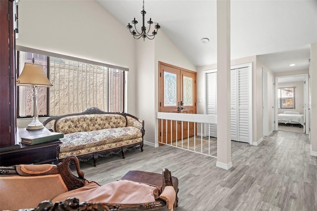 living area featuring a notable chandelier, light hardwood / wood-style floors, and high vaulted ceiling