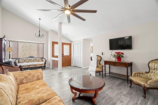 living room with ceiling fan with notable chandelier, hardwood / wood-style floors, and high vaulted ceiling