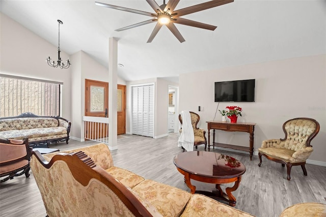 living room featuring vaulted ceiling, ceiling fan with notable chandelier, and light wood-type flooring