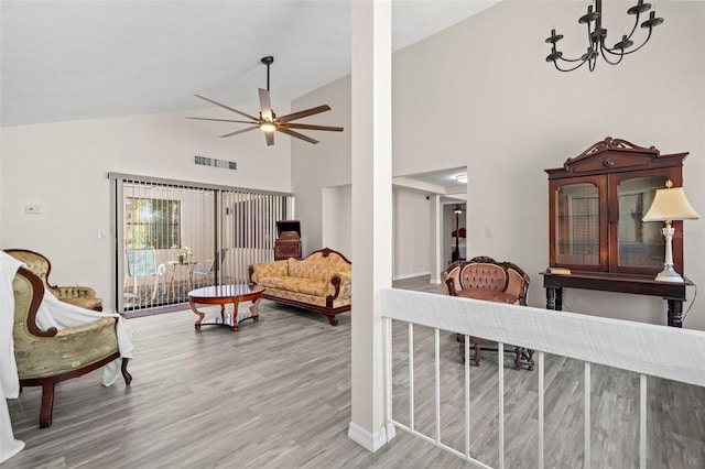 living room with hardwood / wood-style flooring, vaulted ceiling, and ceiling fan with notable chandelier