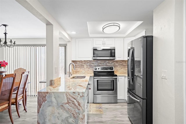 kitchen with a raised ceiling, sink, white cabinets, stainless steel appliances, and light stone countertops