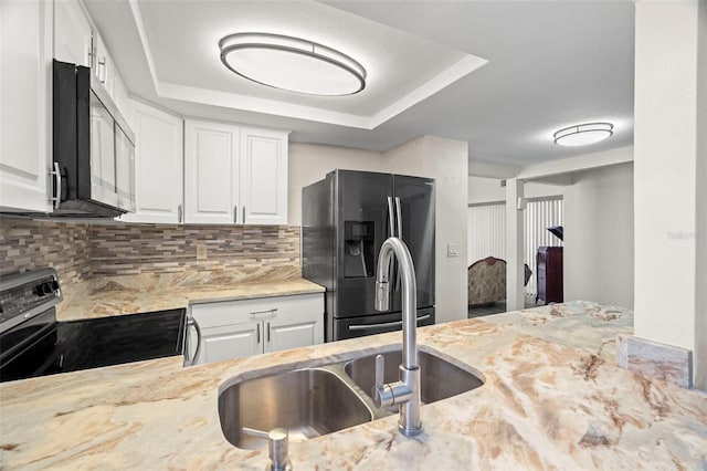 kitchen with appliances with stainless steel finishes, white cabinets, and a tray ceiling