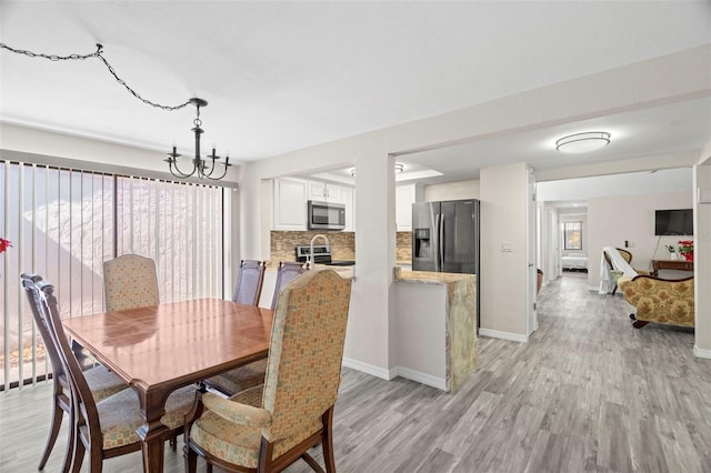 dining space with light hardwood / wood-style floors and a notable chandelier