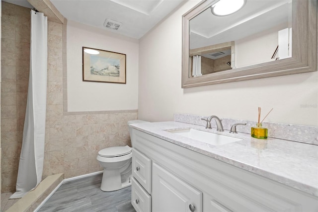 bathroom featuring hardwood / wood-style flooring, tile walls, vanity, toilet, and walk in shower