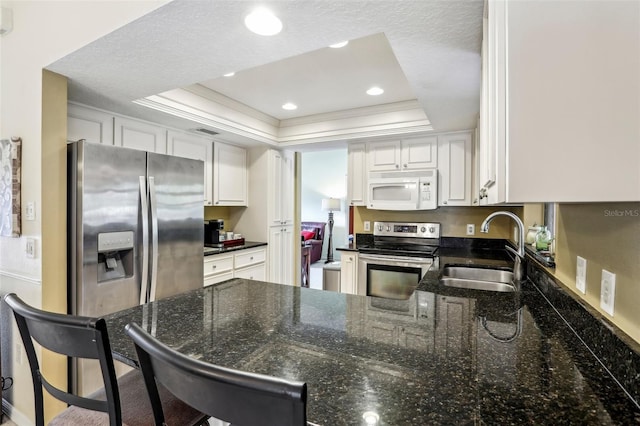 kitchen featuring a breakfast bar, sink, white cabinetry, a tray ceiling, and stainless steel appliances