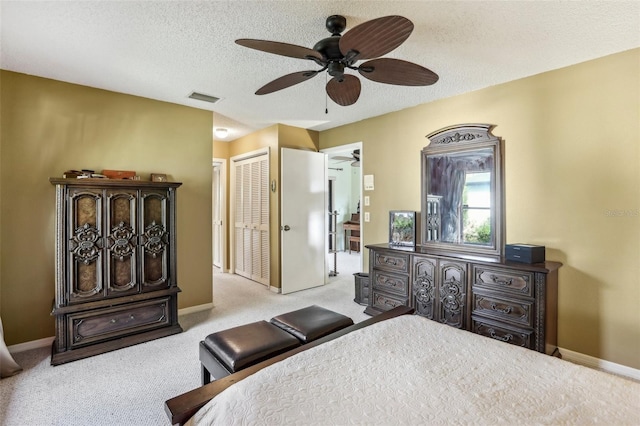 bedroom with ceiling fan, light carpet, a textured ceiling, and a closet