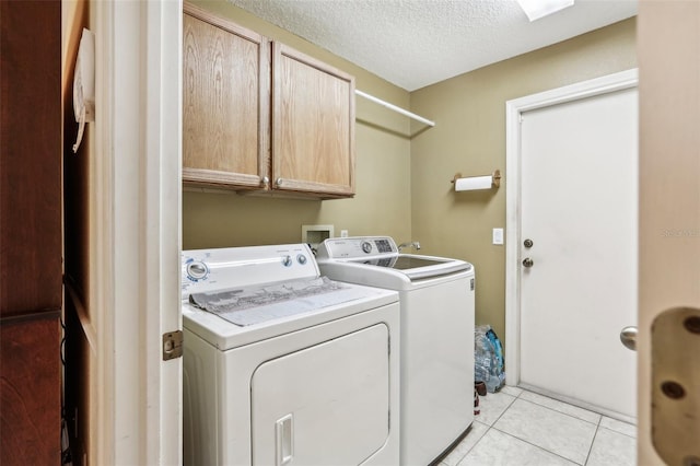 clothes washing area with cabinets, light tile patterned flooring, a textured ceiling, and washer and clothes dryer