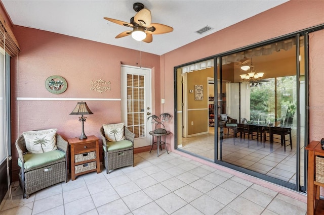 living area with ceiling fan with notable chandelier and light tile patterned floors