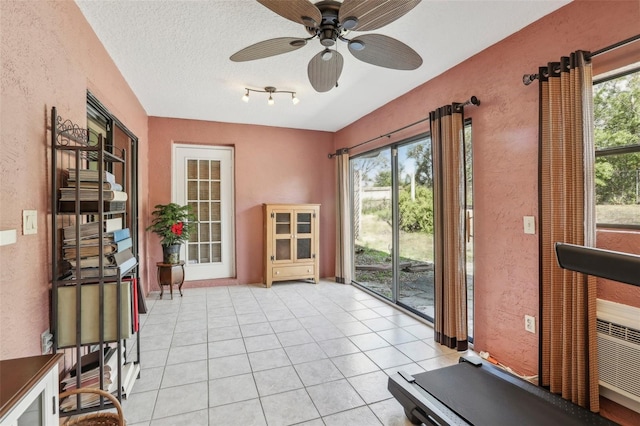 exercise room featuring light tile patterned floors, a textured ceiling, and ceiling fan