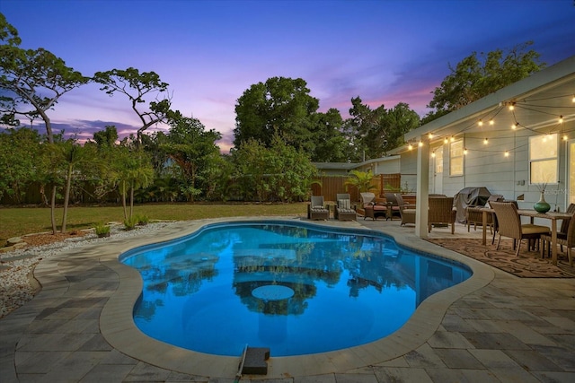 pool at dusk with an outdoor hangout area and a patio area