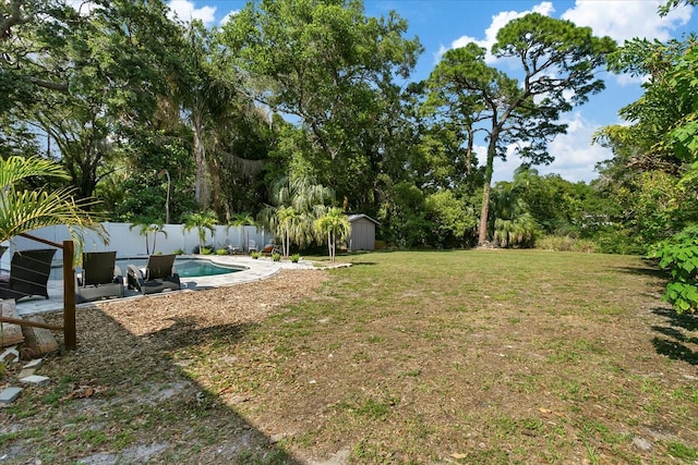 view of yard featuring a fenced in pool and a shed