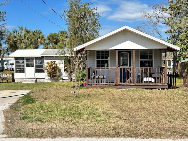 view of front of home with a sunroom, covered porch, and a front lawn