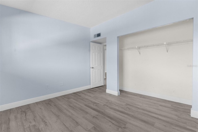 unfurnished bedroom featuring a textured ceiling, light wood-type flooring, and a closet