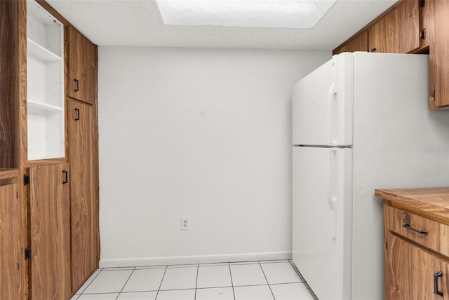 kitchen with light tile patterned floors, a textured ceiling, and white fridge