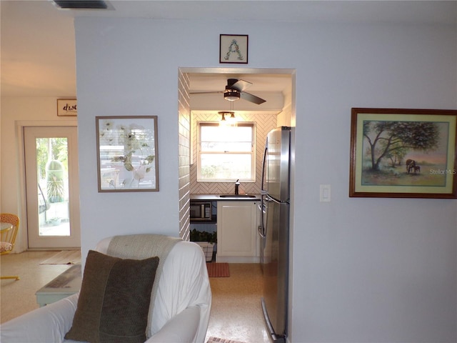 kitchen featuring tasteful backsplash, ceiling fan, sink, and stainless steel refrigerator