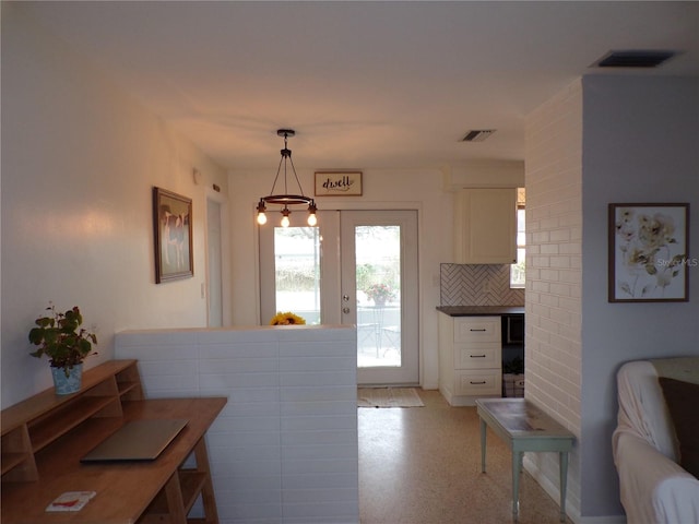 kitchen with white cabinetry, hanging light fixtures, and decorative backsplash