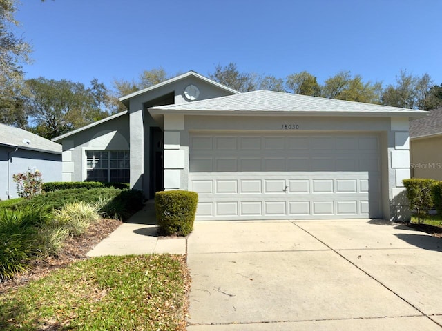 view of front of home featuring concrete driveway, a garage, roof with shingles, and stucco siding