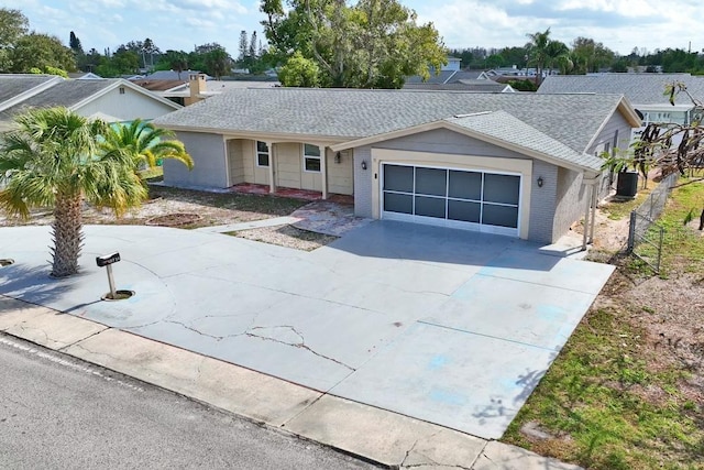 ranch-style home featuring concrete driveway, brick siding, roof with shingles, and an attached garage
