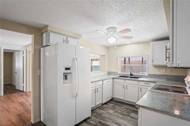 kitchen featuring white appliances, white cabinets, dark wood-type flooring, a textured ceiling, and a sink