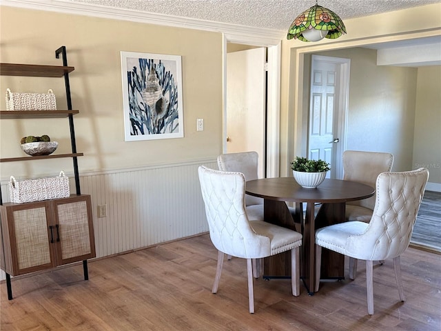 dining room with wainscoting, light wood-style flooring, and a textured ceiling