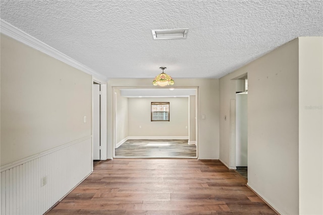 interior space with a textured ceiling, wood finished floors, and visible vents