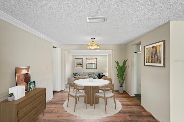 dining room with visible vents, a textured ceiling, and wood finished floors