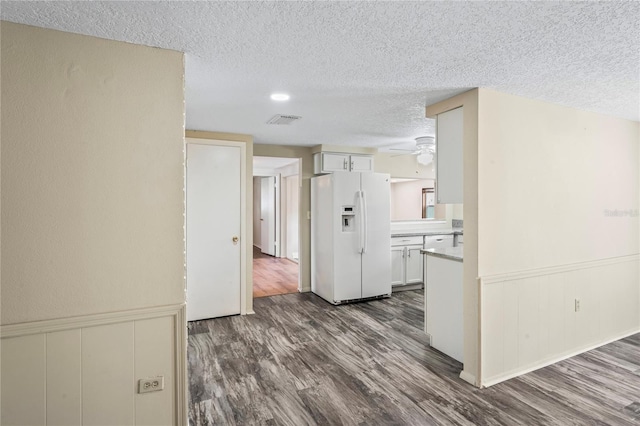 interior space featuring white cabinets, white refrigerator with ice dispenser, light countertops, and dark wood-style flooring