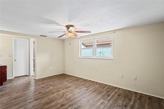 unfurnished room with dark wood-style floors, visible vents, ceiling fan, and baseboards