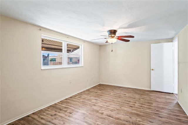 empty room with ceiling fan, wood finished floors, and baseboards