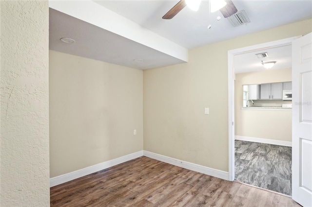 unfurnished room featuring baseboards, visible vents, and wood finished floors