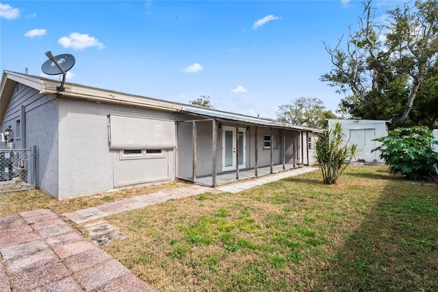 rear view of house with a yard, a patio, stucco siding, a storage unit, and an outdoor structure