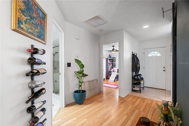 entryway with visible vents, light wood-style flooring, and a textured ceiling