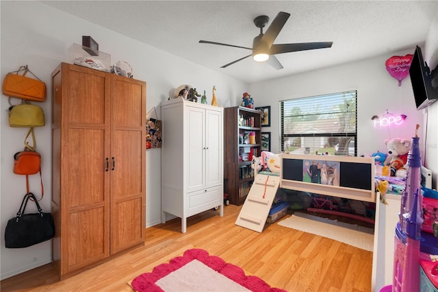 bedroom featuring light wood-type flooring, a ceiling fan, and a textured ceiling