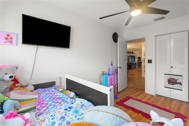 bedroom with light wood-type flooring, ceiling fan, visible vents, and a closet