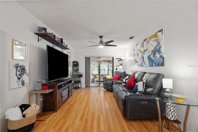 living area with a ceiling fan, light wood-type flooring, visible vents, and a textured ceiling