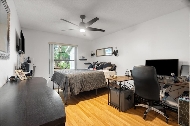 bedroom with a textured ceiling, a ceiling fan, and wood finished floors