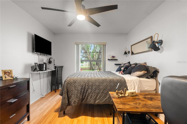 bedroom with a ceiling fan, light wood-type flooring, and a textured ceiling