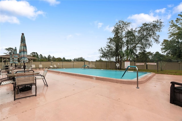 community pool with a patio area and fence