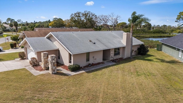 view of front of property featuring a water view, a garage, and a front lawn